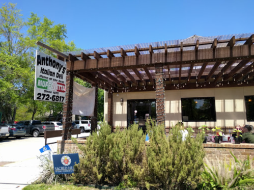 A sunny view of Anthony's Italian Deli with outdoor seating and a sign displaying the restaurant's name and contact number.