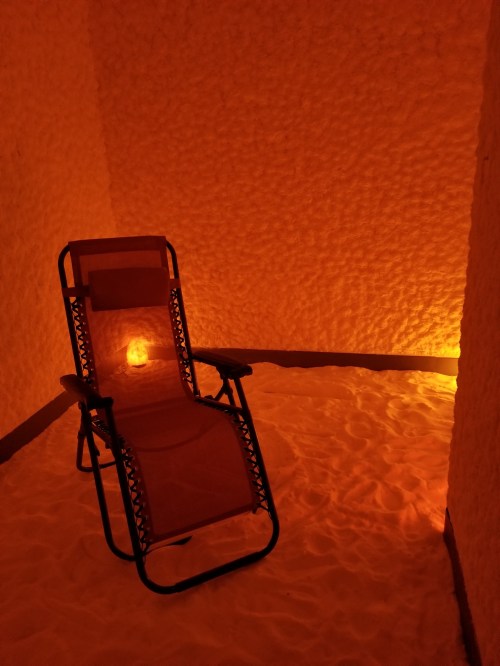 A cozy salt room with a reclining chair and soft orange lighting, creating a relaxing atmosphere.