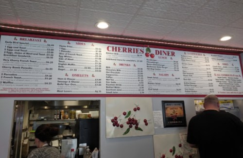 Menu board at Cherries Diner featuring breakfast, sides, omelets, and drinks with prices listed.