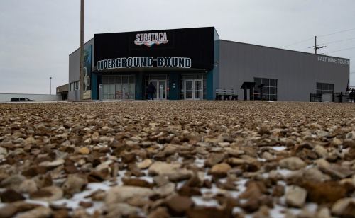 A building labeled "Underground Bound" with a gravel foreground, cloudy sky, and a sign for salt mine tours.