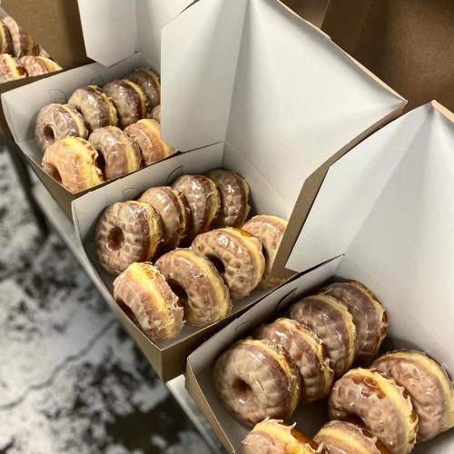 Boxes of glazed donuts arranged neatly, showcasing their shiny, golden-brown tops and fluffy textures.