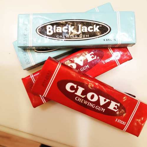 Three packs of chewing gum: one blue labeled "Black Jack" and two red labeled "Clove," each containing five sticks.