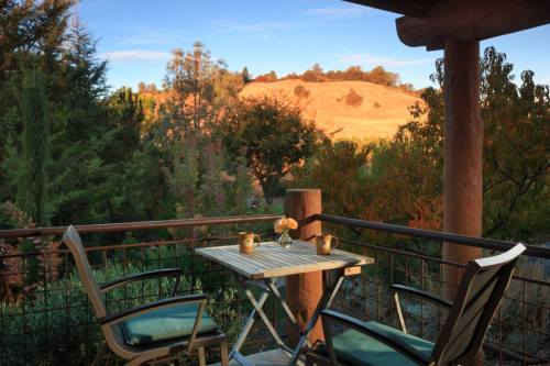 A cozy balcony with two chairs and a small table, overlooking a scenic landscape of hills and trees.