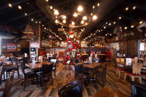 Cozy restaurant interior decorated for the holidays, featuring a Christmas tree and festive lights.