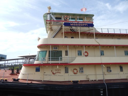 A close-up of the side of a riverboat named "Mississippi," featuring lifebuoys and an American flag.