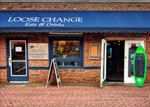 Exterior of Loose Change Eats & Drinks, featuring a blue awning, brick facade, and two doors with signs.