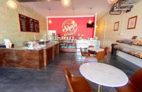 Interior of a candy shop with a red accent wall, wooden counter, and round tables. Bright and inviting atmosphere.
