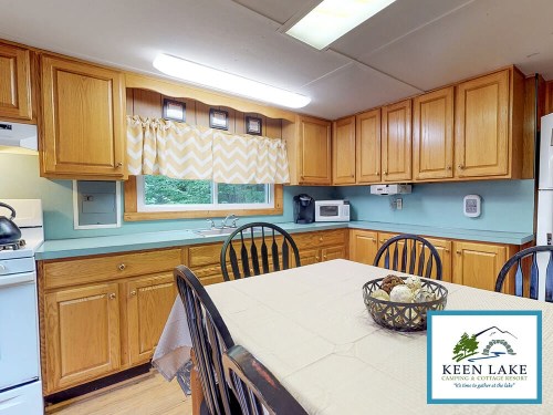 Cozy kitchen with wooden cabinets, a table set for dining, and modern appliances in a rustic cabin setting.