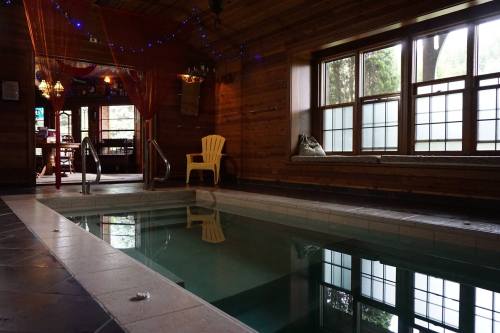 Indoor pool area with wooden walls, a yellow chair, and soft lighting from decorative elements.