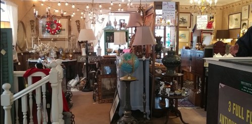 A cozy antique shop filled with various vintage items, lamps, and decor, illuminated by warm string lights.