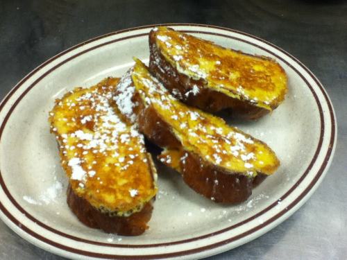 Three slices of golden-brown French toast dusted with powdered sugar on a beige plate.