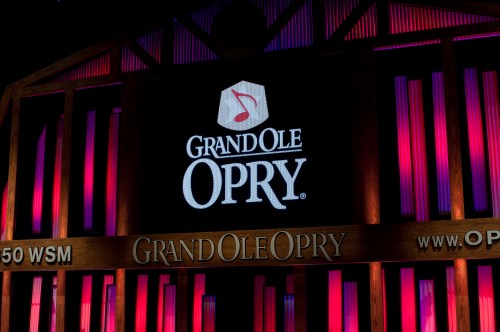 Logo of the Grand Ole Opry displayed on a stage backdrop with colorful lighting.