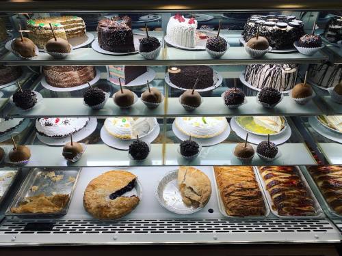 A display case filled with various cakes, cupcakes, and pastries, including chocolate-covered treats and fruit tarts.