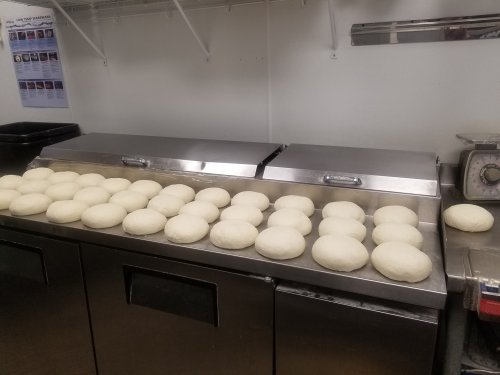 A countertop with multiple round dough balls resting, ready for baking in a kitchen setting.