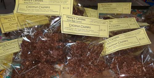 A display of packaged coconut clusters from Henry's Candies, each labeled with price and ingredients.