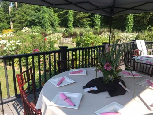 A beautifully set outdoor table with pink napkins, surrounded by a lush garden in the background.
