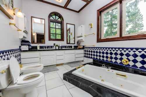 Spacious bathroom featuring a bathtub, dual sinks, and a window with a view, accented by blue and white tiles.