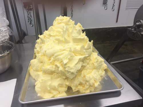 A large mound of freshly made butter on a metal tray in a kitchen setting.