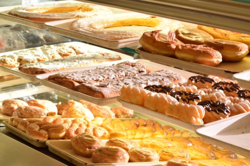 A display case filled with various pastries, including donuts, danishes, and sweet rolls, all beautifully arranged.