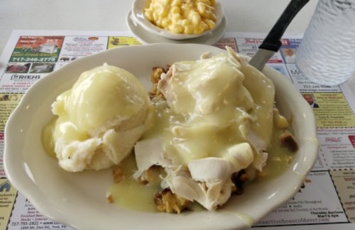 A plate of turkey and gravy over stuffing, served with mashed potatoes and a side of macaroni and cheese.