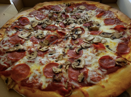 A close-up of a pepperoni and mushroom pizza with melted cheese, served in a pizza box.