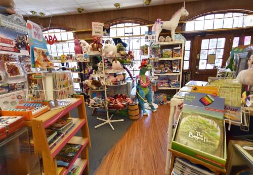A colorful toy store filled with shelves of stuffed animals, books, and games, featuring a whimsical decor.