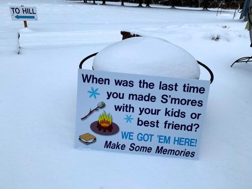 A sign in the snow asks when you last made s'mores, inviting people to create memories with friends or family.