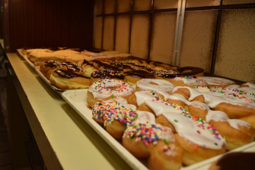 A display of assorted donuts, including glazed, chocolate, and sprinkles, arranged on a tray.