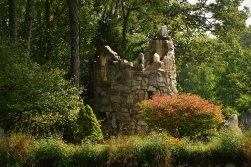 A stone ruin surrounded by lush greenery and colorful foliage in a serene forest setting.