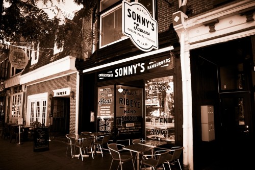 A vintage-style restaurant exterior with a sign reading "Sonny's Hamburgers" and outdoor seating.