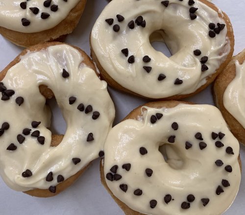 A close-up of donuts topped with creamy frosting and sprinkled with mini chocolate chips.