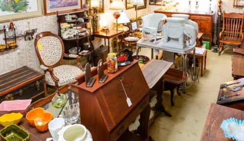 A cozy antique shop filled with various vintage furniture, decor items, and collectibles arranged throughout the space.