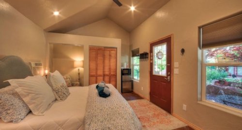 Cozy bedroom with a bed, closet, and a door leading to a garden view, featuring warm lighting and soft decor.