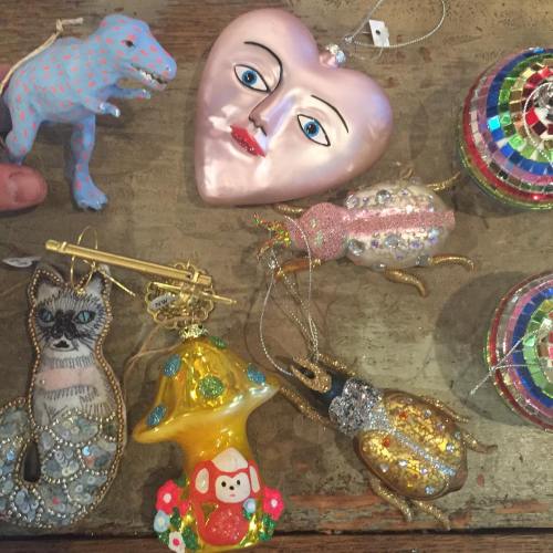 A collection of colorful ornaments, including a heart, animals, and a mushroom, arranged on a wooden surface.