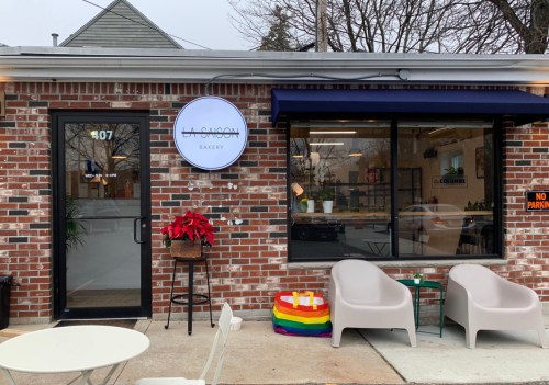 Exterior of La Cuison Bakery featuring a brick facade, a sign, outdoor seating, and colorful decor.