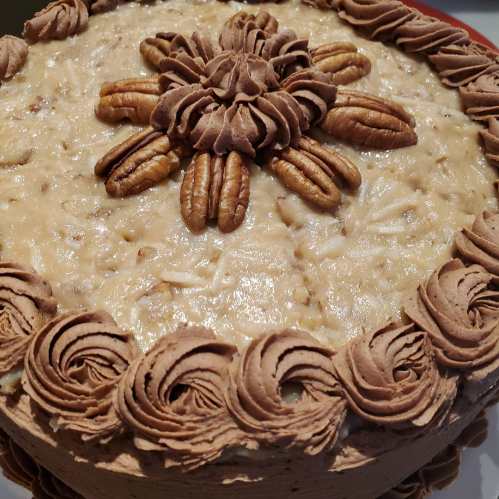 A beautifully decorated cake topped with chocolate frosting, pecans, and a floral design.