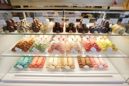 A display case filled with colorful macarons and chocolate-covered treats in various flavors.