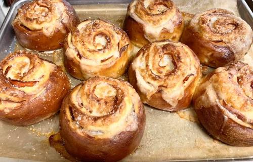 Freshly baked cinnamon rolls with a golden-brown crust and a sweet glaze, arranged on a baking tray.