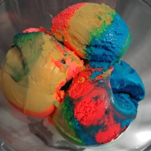 A bowl filled with vibrant, multicolored scoops of ice cream in shades of blue, pink, yellow, and green.