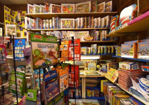 A colorful display of books and educational materials fills a cozy store, with shelves and racks overflowing with items.