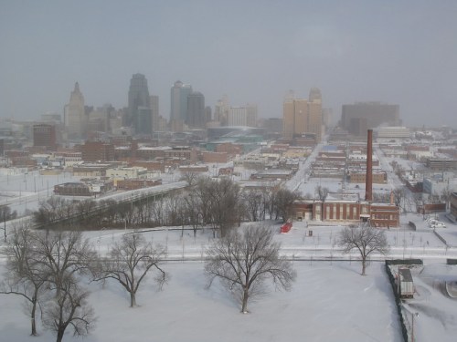 A snowy cityscape featuring tall buildings and a winter landscape in an urban area.