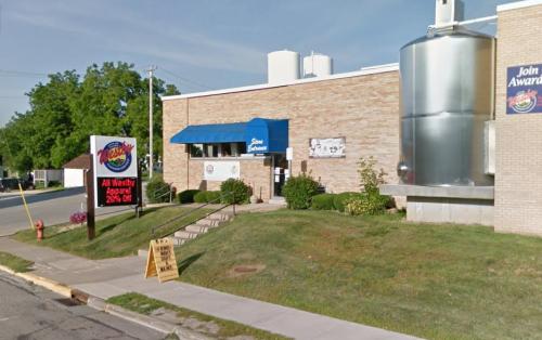 A brick building with a blue awning, a large silver tank, and a sign advertising a sale on apparel.