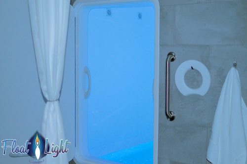 A serene view through a window showing a blue-lit space, with a towel hanging nearby and a handle on the wall.