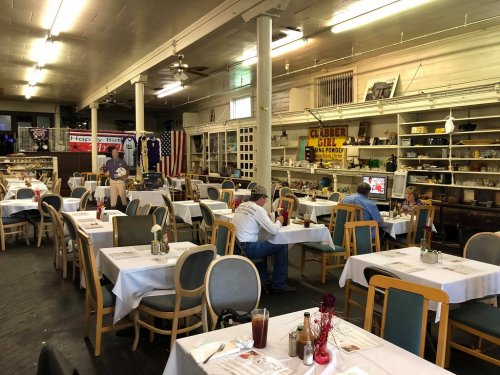 A spacious restaurant with empty tables, vintage decor, and a few diners enjoying their meals.