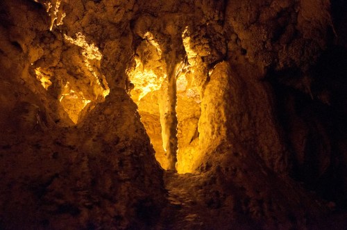 A dimly lit cave interior with glowing formations and stalactites, creating an ethereal atmosphere.