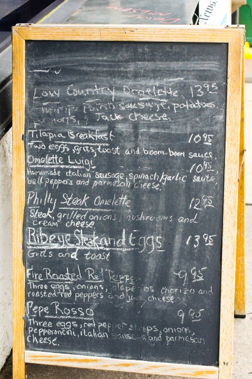 Chalkboard menu featuring breakfast items like omelettes, steak, and eggs with prices listed.