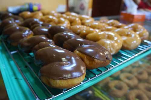 A display of glazed and chocolate-covered donuts on a cooling rack.