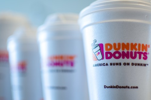 Close-up of multiple Dunkin' Donuts cups with the logo and slogan, "America Runs on Dunkin'."