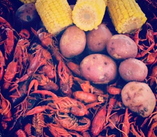 A colorful spread of boiled crawfish, corn on the cob, and red potatoes.