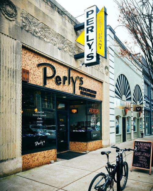 Exterior of Perly's Restaurant with a bike parked outside and a sign advertising Hanukkah specials.